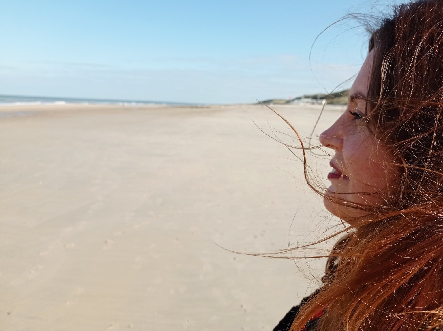 Persoon kijkt uit over het strand