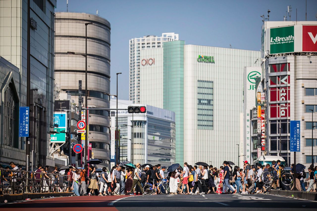 A busy street crossing in Tokyo with diverse people and modern architecture.